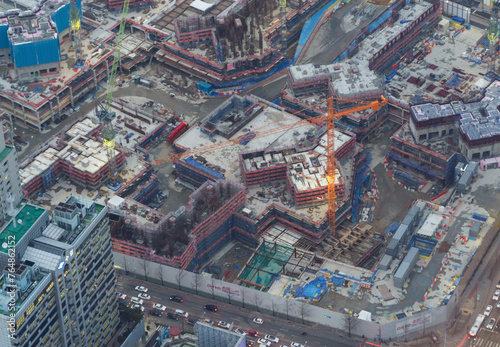 Aerial view of busy industrial construction site workers with cranes working. Top view of development high rise architecture building.