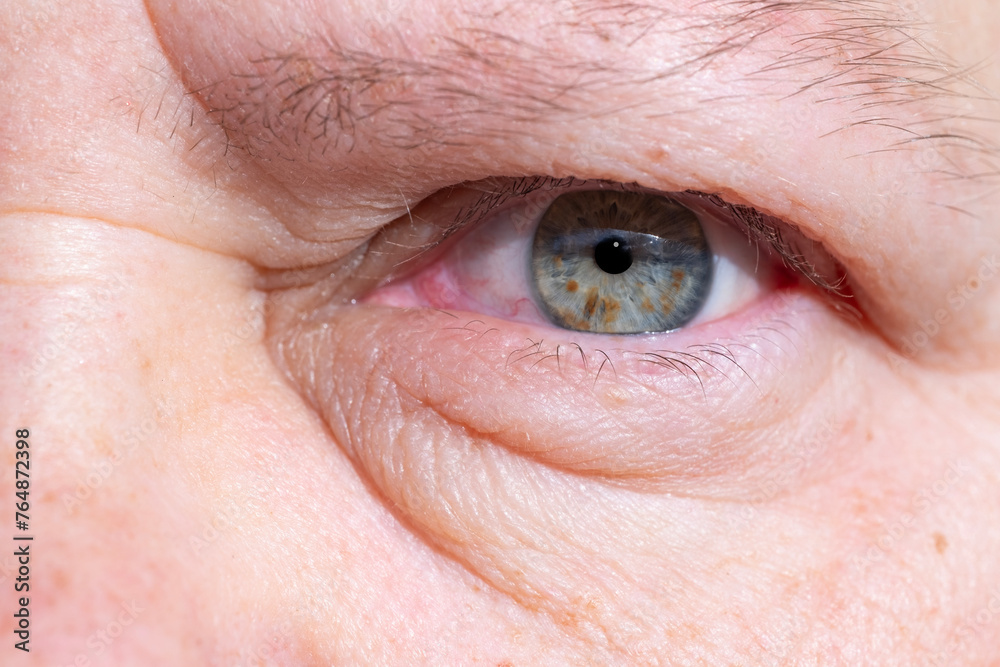 Fototapeta premium close-up mature woman's eye, revealing natural signs aging such wrinkles and puffiness under lower eyelid, yet still conveying strength, resilience, and wisdom