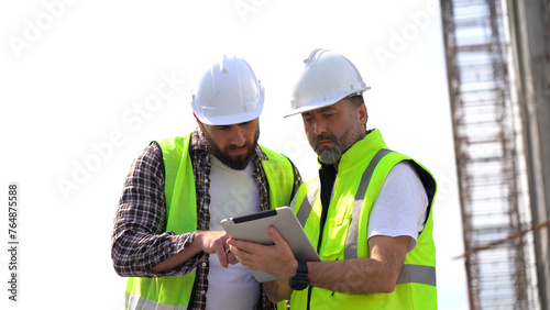 team of Construction workers Senior architect or civil engineer and foreman walking and discussion to inspection or checking structure apartment with tablet computer at construction site. building