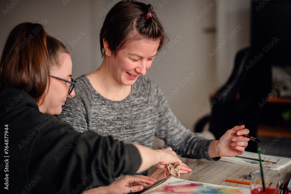 Fototapeta premium Two friends share laughter and joy while engaged in watercolor painting, illustrating the pleasure of artistic hobbies.
