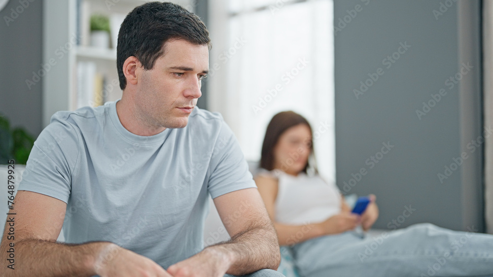 Beautiful couple sitting on sofa silent with problem using smartphone at home Beautiful couple sitting on sofa silent with problem using smartphone at home