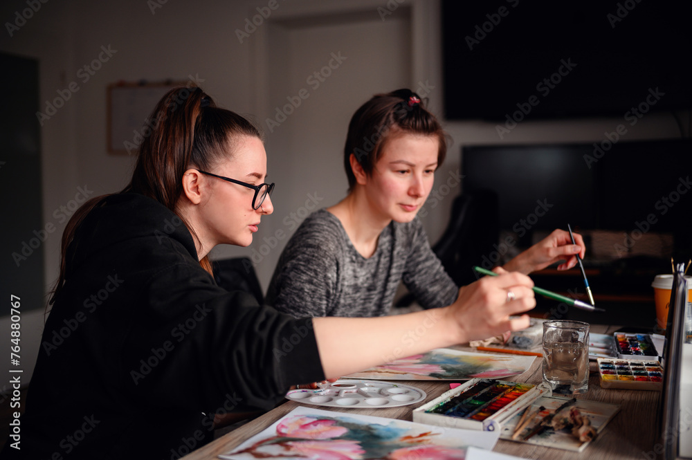 Fototapeta premium Two artists deeply focused on their watercolor techniques, a synergy of concentration and creativity fills the room
