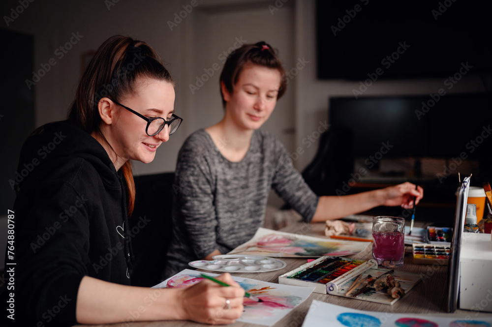 Fototapeta premium Two artists deeply focused on their watercolor techniques, a synergy of concentration and creativity fills the room