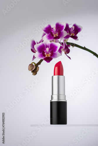 An elegant image showcasing a vibrant pink lipstick beside a beautiful purple orchid flower
