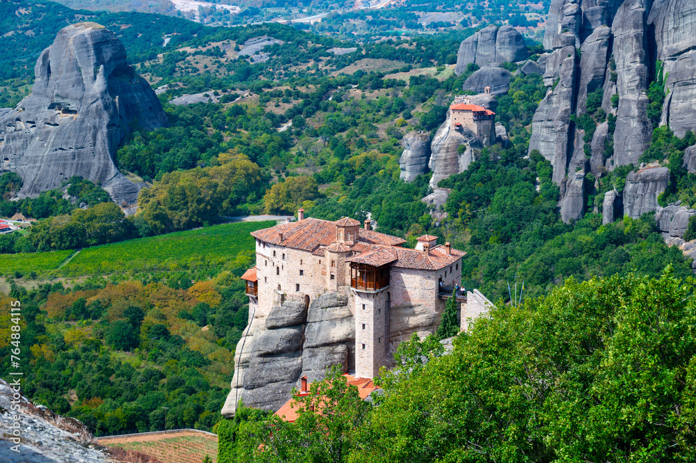 Monastery Meteora Greece. Stunning summer panoramic landscape. View at mountains and green forest against epic blue sky with clouds. UNESCO heritage list object.
