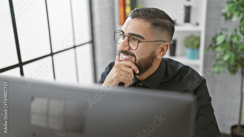 Handsome young man with beard smiling in modern office setting