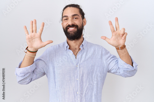 Hispanic man with beard wearing casual shirt showing and pointing up with fingers number eight while smiling confident and happy. © Krakenimages.com