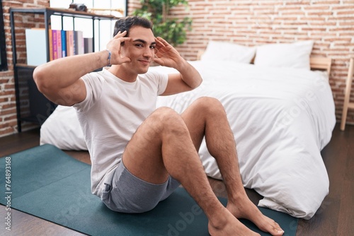 Young hispanic man smiling confident training abs exercise at bedroom