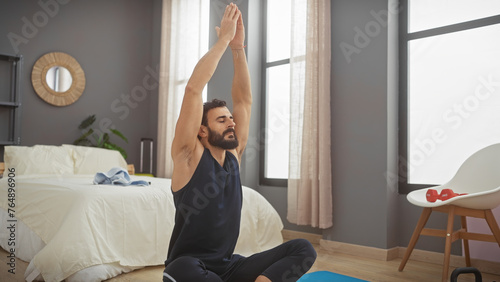 A bearded man in a bedroom practicing yoga in a serene indoor environment, illustrating wellness and home exercise.