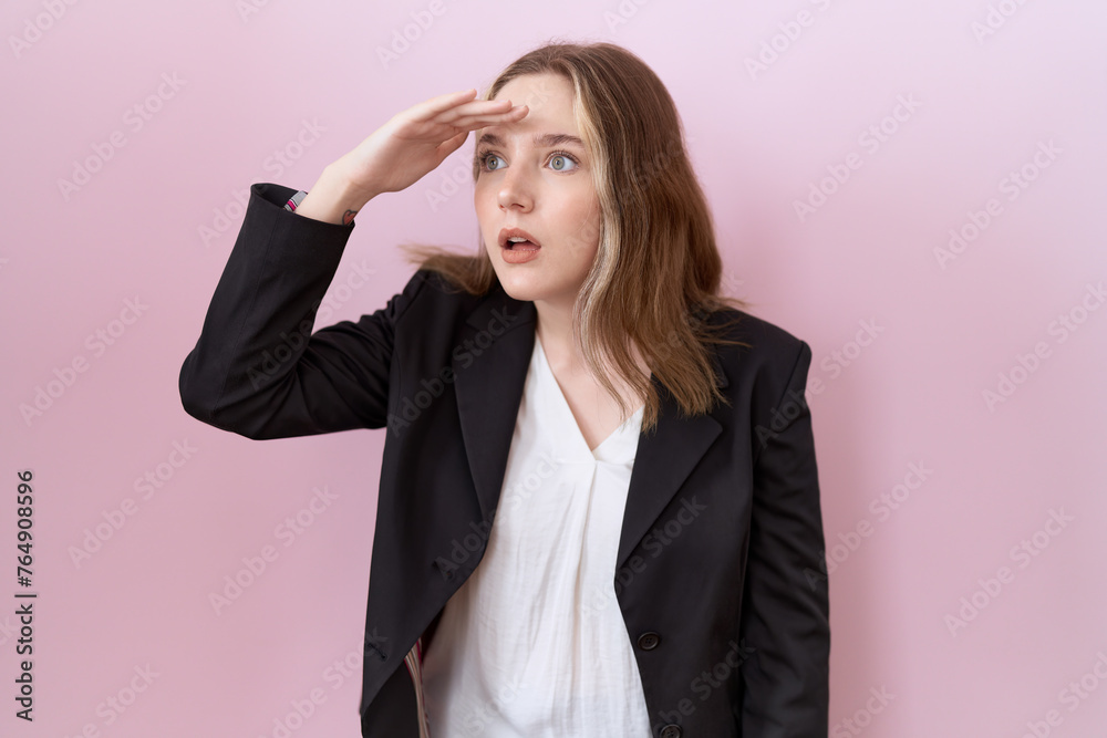 Young caucasian business woman wearing black jacket very happy and smiling looking far away with hand over head. searching concept. Young caucasian business woman wearing black jacket very happy and smiling looking far away with hand over head. searching concept.