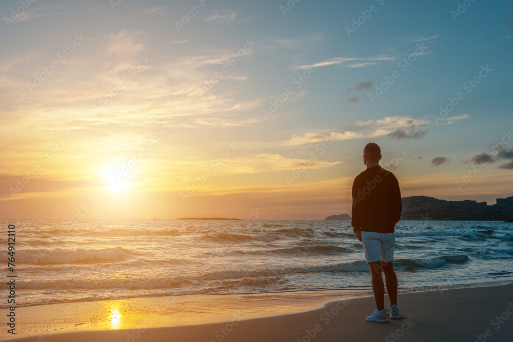 Man traveller on a tropical beach during sunset. Holiday vacation and travel concept.