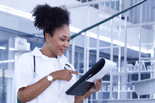 young african american woman doctor reading medical research from clipboard in lab at hospital. female doctor student studying medical report in laboratory in university. medical education.