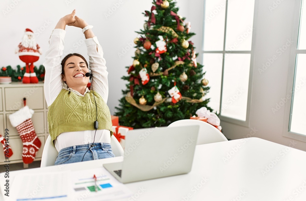 Young beautiful hispanic woman call center agent relaxed sitting by christmas tree at home Young beautiful hispanic woman call center agent relaxed sitting by christmas tree at home
