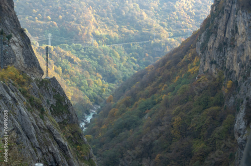 The outlines of the mountain range in autumn. A mountain gorge high in the mountains. Transmission of electrical energy in the mountains. Experience power lines in the mountains.