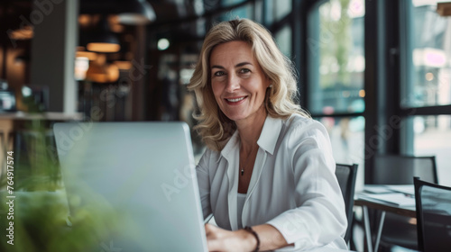 Cheerful mature professional using a laptop in a casual office setting