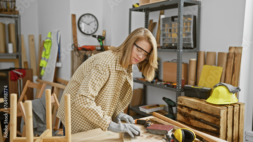A focused woman sands wood in a well-equipped carpentry workshop, embodying craftsmanship and precision. photo