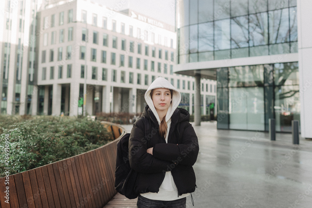 Fototapeta premium Tourist teenage girl traveling alone through the city streets in the autumn-winter season. Modern solo travel, lone traveler, Winter vacation railroad adventure concept.