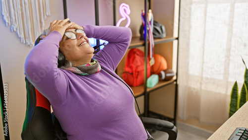 Fotografie Mature woman relaxing in a modern gaming room with neon light, reflecting leisure time at home