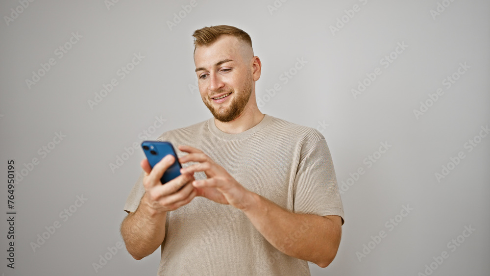 Attractive young man with beard smiling at smartphone against white isolated background Attractive young man with beard smiling at smartphone against white isolated background
