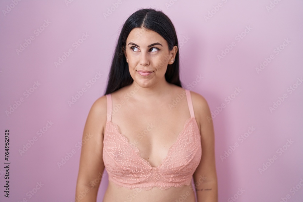 Young hispanic woman wearing pink bra smiling looking to the side and staring away thinking. Young hispanic woman wearing pink bra smiling looking to the side and staring away thinking.