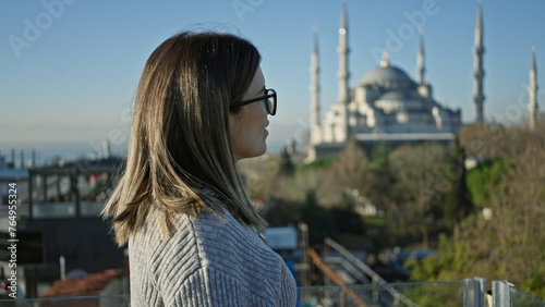 A contemplative woman admires the iconic blue mosque from a terrace in istanbul, showcasing travel and architecture. © Krakenimages.com