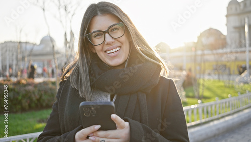 A smiling young adult woman enjoys using her smartphone at taksim square with taksim mosque in the background during a sunny day in istanbul. photo