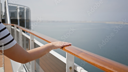 Woman enjoys a peaceful cruise vacation, leaning on the ship's deck rail, gazing at the sea.