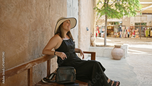 Photography Smiling woman tourist wearing a sunhat and casual clothes enjoys her visit at a traditional souq in dubai, expressing leisure and culture