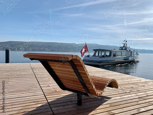 Sitzplatz - Entspannungsliege am See / Holzliege zur Entspannung am Zürichsee in Thalwil, Schiff / Kursschiff der Schifffahrt fährt vorbei.