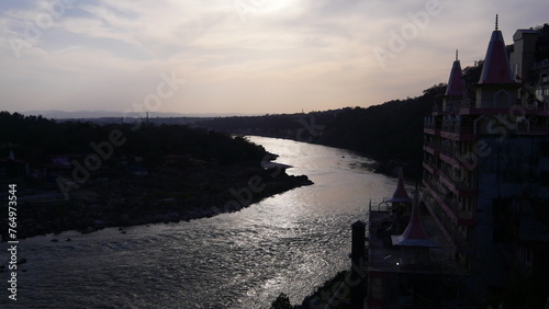 Vue du gange à travers un village indien, dans une zone montagnard, baignade, couché du Soleil, sombre, ambiance amicale et touristique, petite maison près du fleuve et flanc, beauté urbaine hindu,  photo