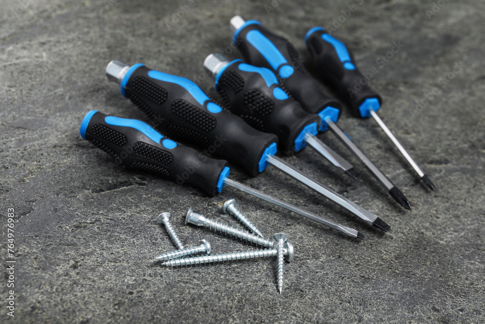 Naklejka premium Set of screwdrivers and screws on grey table