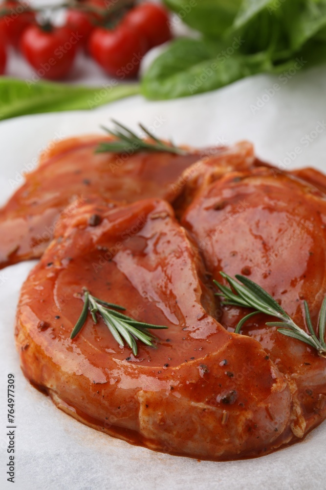 Raw marinated meat and rosemary on parchment, closeup