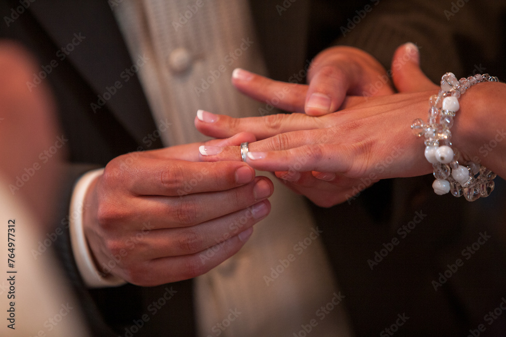 This photograph captures a poignant moment within a wedding ceremony: the gentle placement of a wedding band on the bride's finger. The focus on their hands against the soft background evokes the This photograph captures a poignant moment within a wedding ceremony: the gentle placement of a wedding band on the bride's finger. The focus on their hands against the soft background evokes the