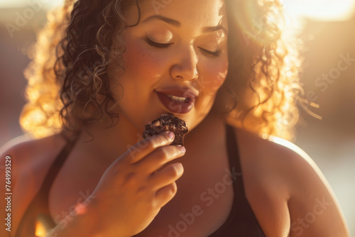 A plus-size model eating a piece of dark chocolate after a strength training session