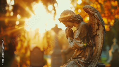 Angel statue praying on graveyard. Golden hour autumn cemetery. In loving memory