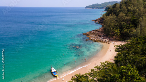 beach and sea on a beautiful sunny day. Palm branch in the foreground of a seascape. Sea waves on sand and boat tourist . Natural landscape of the andaman Ocean Thailand ,Travel concept