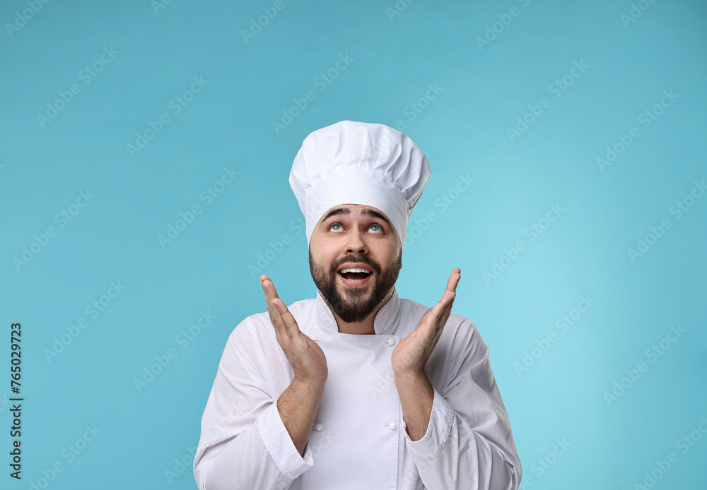 Happy young chef in uniform on light blue background Happy young chef in uniform on light blue background