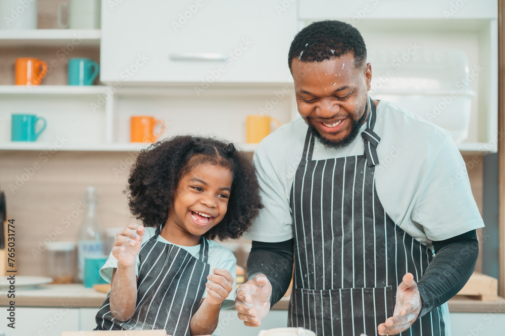 © chokniti - In a home kitchen, black father and his daughter bond over cooking a meal food, their laughter and love filling the air, embodying the joy of African American family life, Father's Day concept