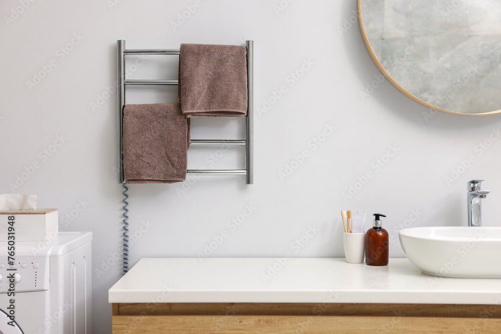 Fototapeta premium Heated towel rail with brown towels in bathroom