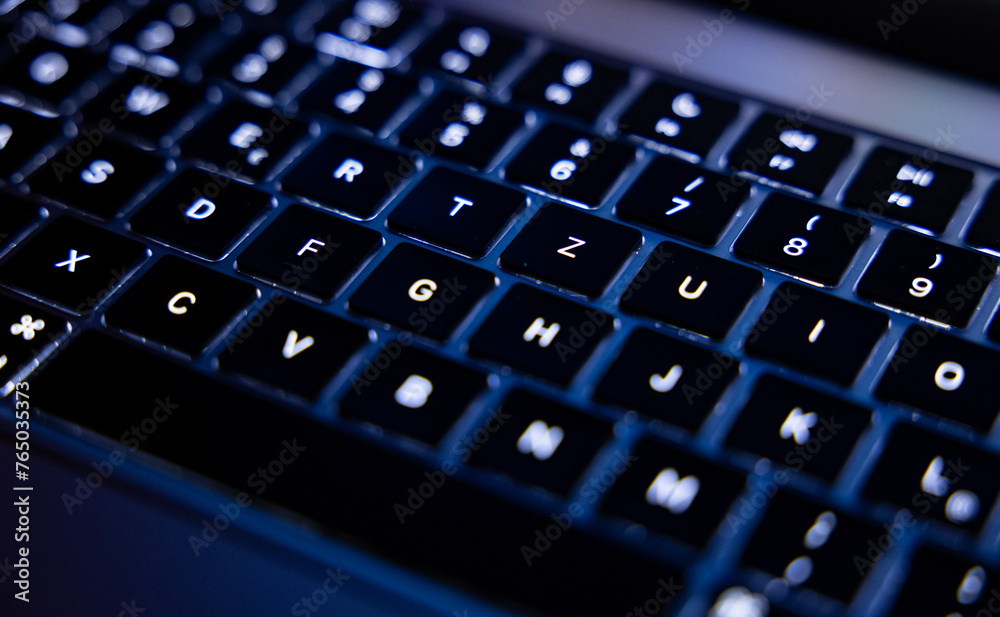 Close-up of illuminated computer keyboard. The keys are black with white letters and characters. Close-up of illuminated computer keyboard. The keys are black with white letters and characters.