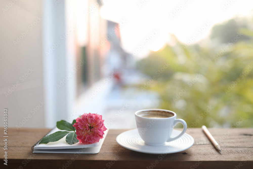 ceramic coffee cup and a white vase of rose flowers and notebooks ceramic coffee cup and a white vase of rose flowers and notebooks