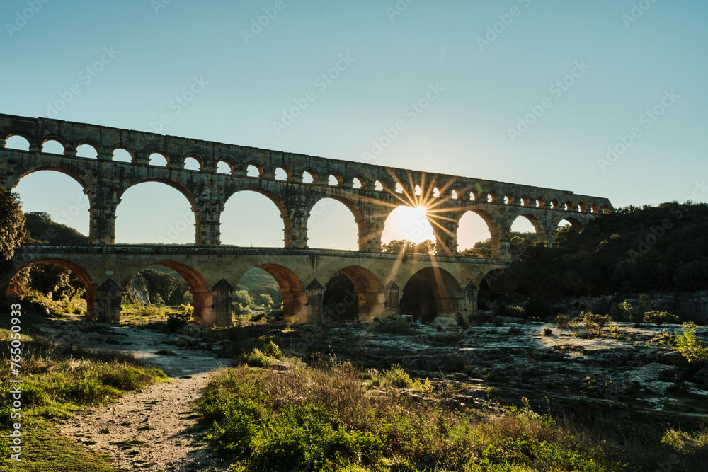illuminated ancient Roman aqueduct Pont du Gard near Languedoc, France, built as part of the infrastructure for water supply of the roman empire. - obrazy, fototapety, plakaty 