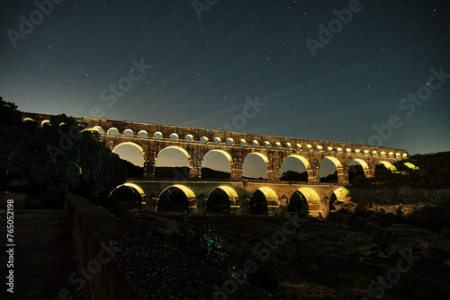 illuminated ancient Roman aqueduct Pont du Gard near Languedoc, France, built as part of the infrastructure for water supply of the roman empire.