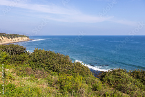 a beautiful spring landscape at Point Dume beach with blue ocean water, lush green trees and plants, homes along the cliffs, waves, blue sky and clouds in Malibu California USA © Marcus Jones