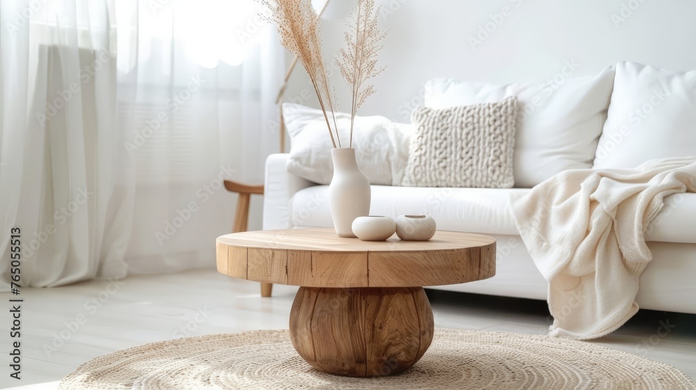 a round wooden coffee table in front of a white sofa in a scandinavian styled living room - obrazy, fototapety, plakaty 