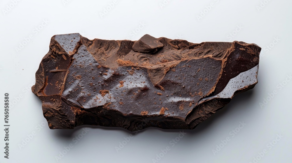 A macro shot of a textured slab of dark chocolate with rich tones and natural cocoa bean fragments against a clean white background.