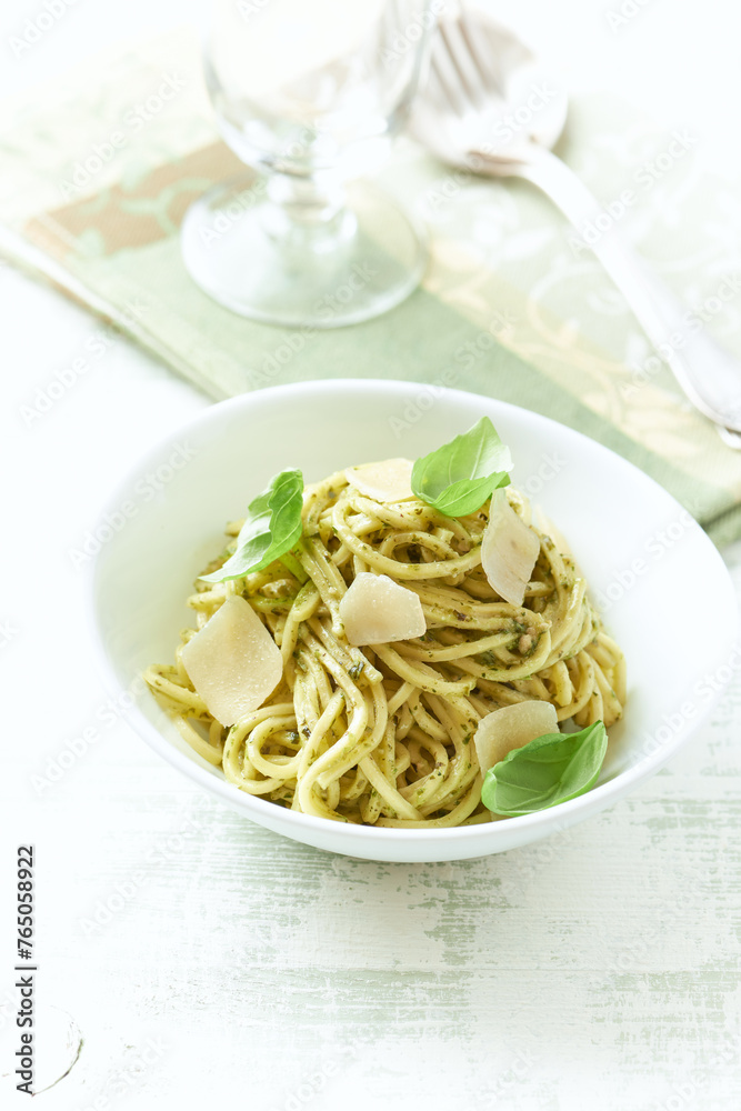 Spaghetti with olive pesto sauce and fresh basil. Bright wooden background. Close up	