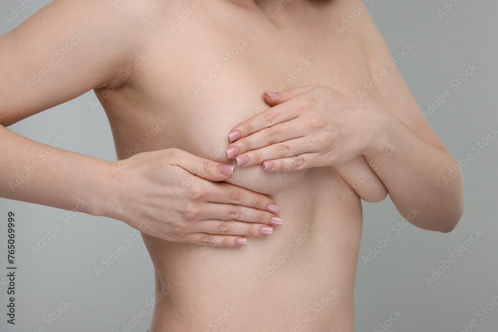 Mammology. Naked young woman doing breast self-examination on light grey background, closeup