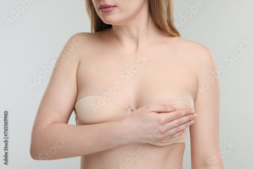 Mammology. Young woman doing breast self-examination on light grey background, closeup