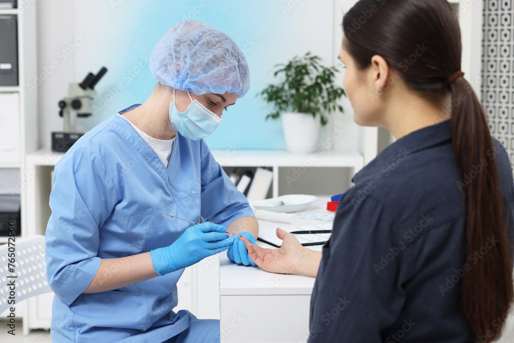Fototapeta premium Laboratory testing. Doctor taking blood sample from patient at white table in hospital